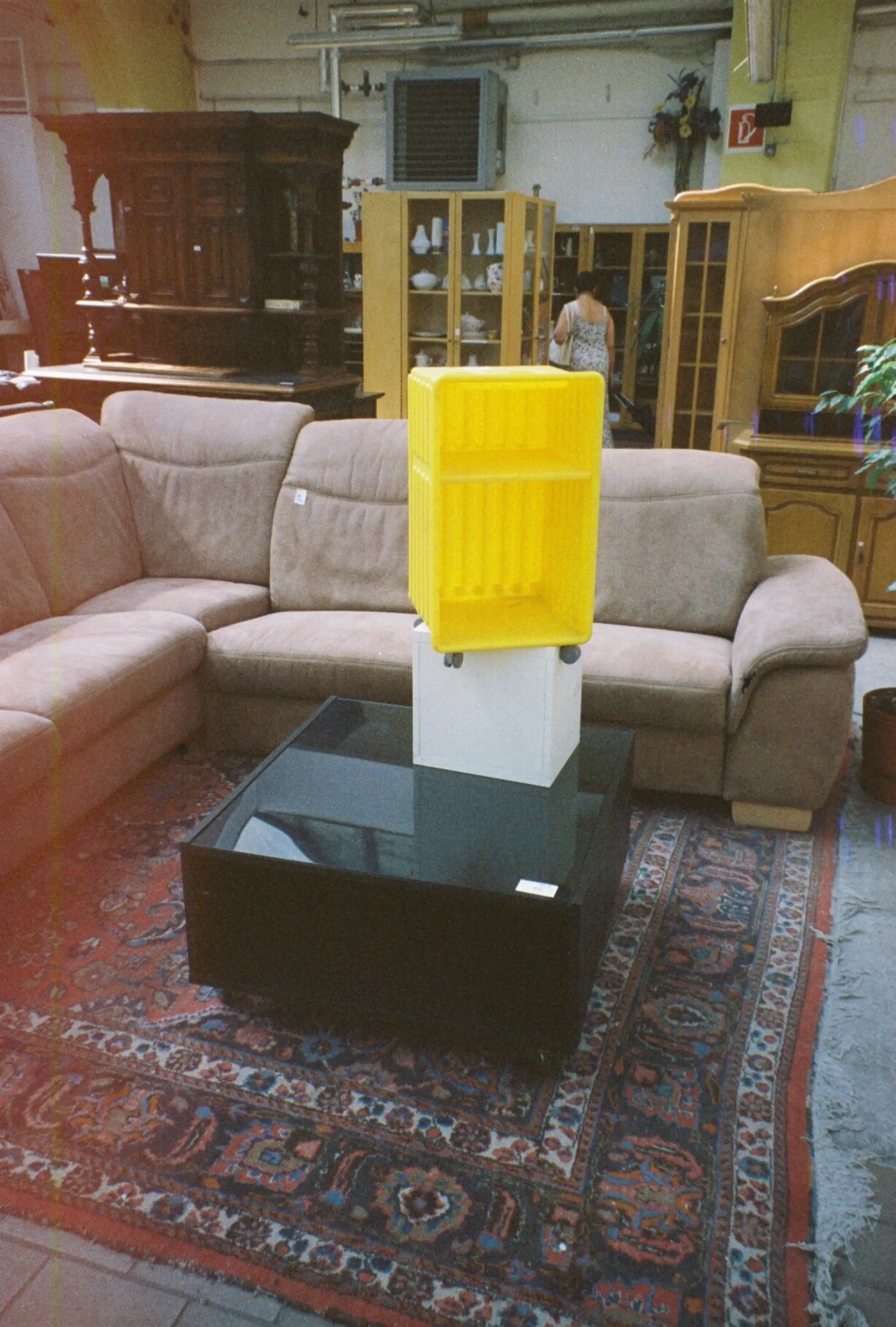 Foto von Lagerraum mit verschiedenen Holzschränken im Hintergrund, im Vordergrund steht ein Sofa und ein Beistelltisch, auf dem Beistelltisch balancieren zwei Boxen