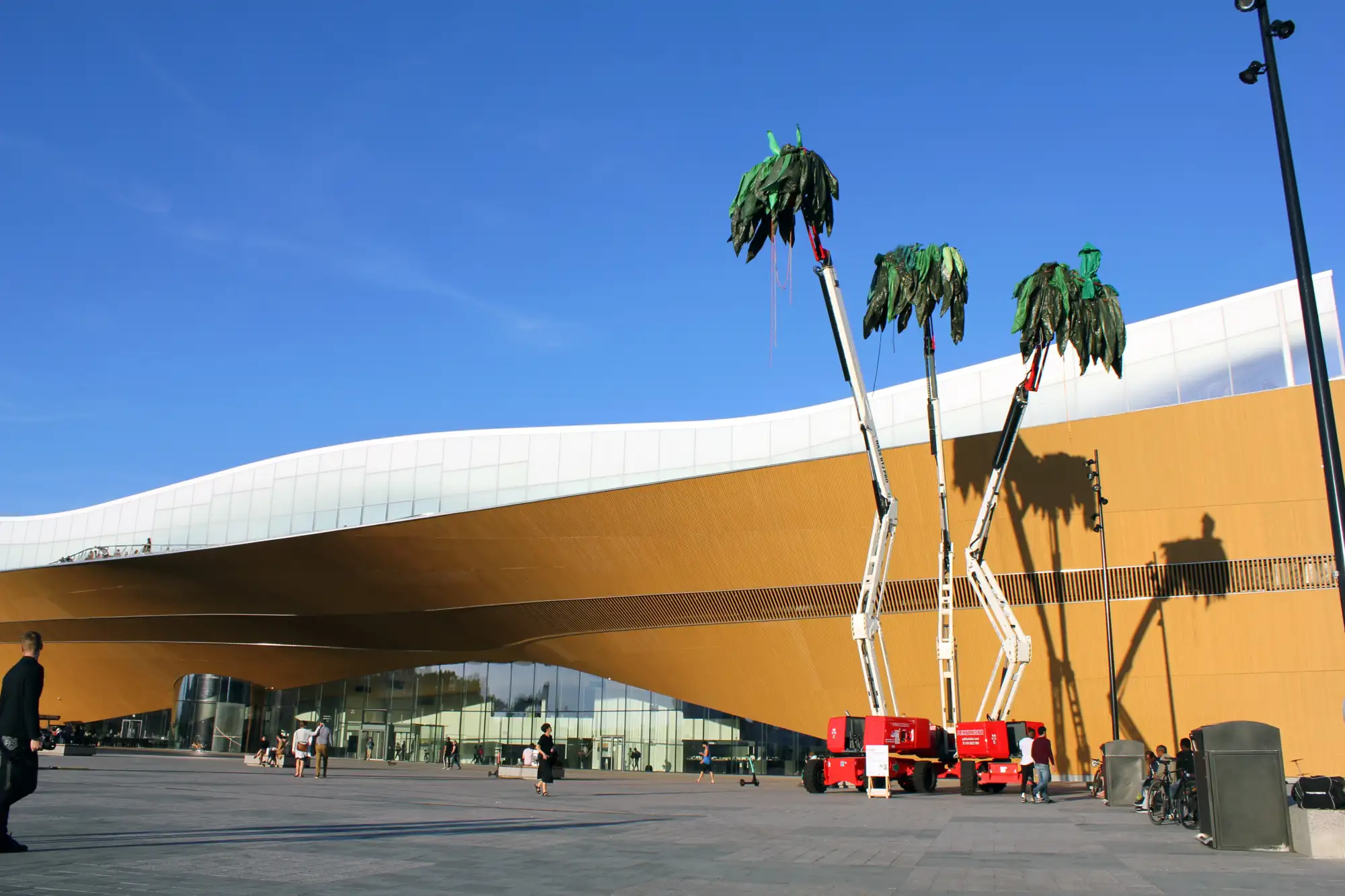 Nachgebaute Palmen in hochgestreckten, mobilen Kränen.