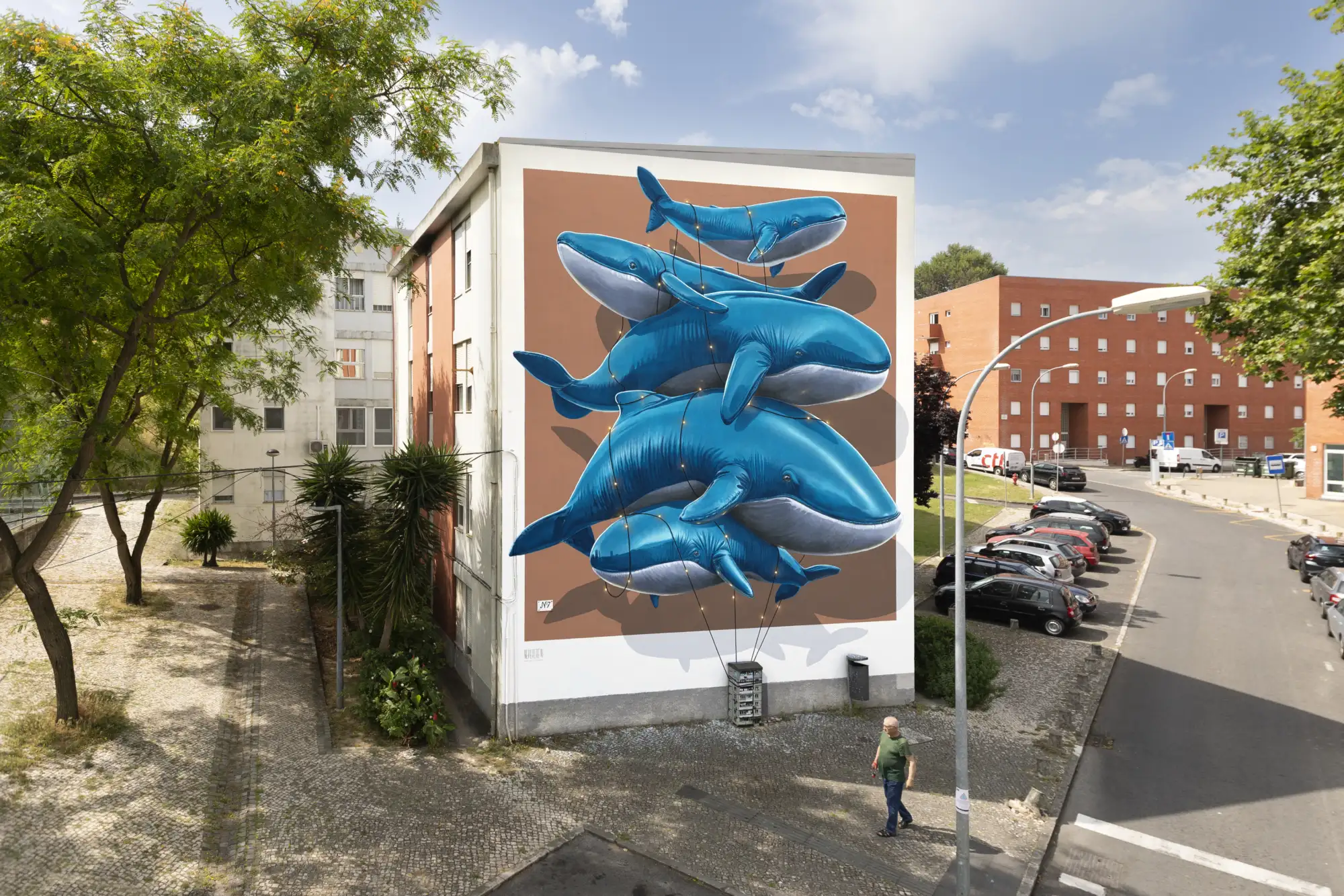 Eine Hauswand, bemalt mit sich übereinandertürmenden Walen