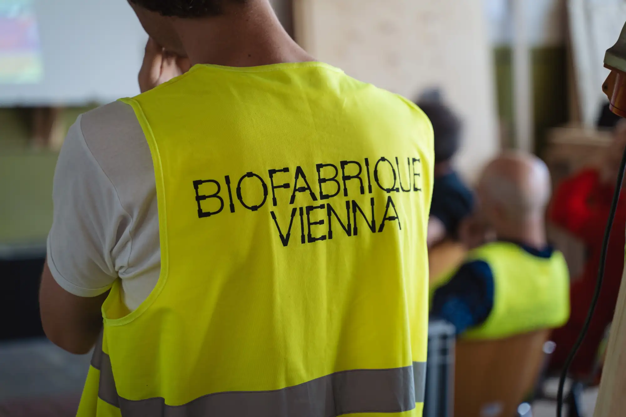 Mann von hinten mit gelber Weste und Aufschrift "Biofabrique Vienna"
