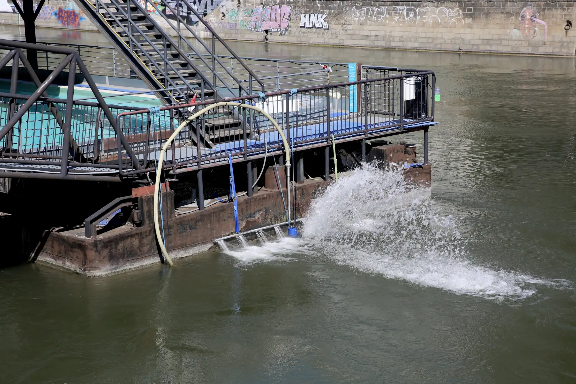An der Hinterseite des Badeschiffs sprudelt weißes Wasser, als würde sich das Schiff fortbewegen.