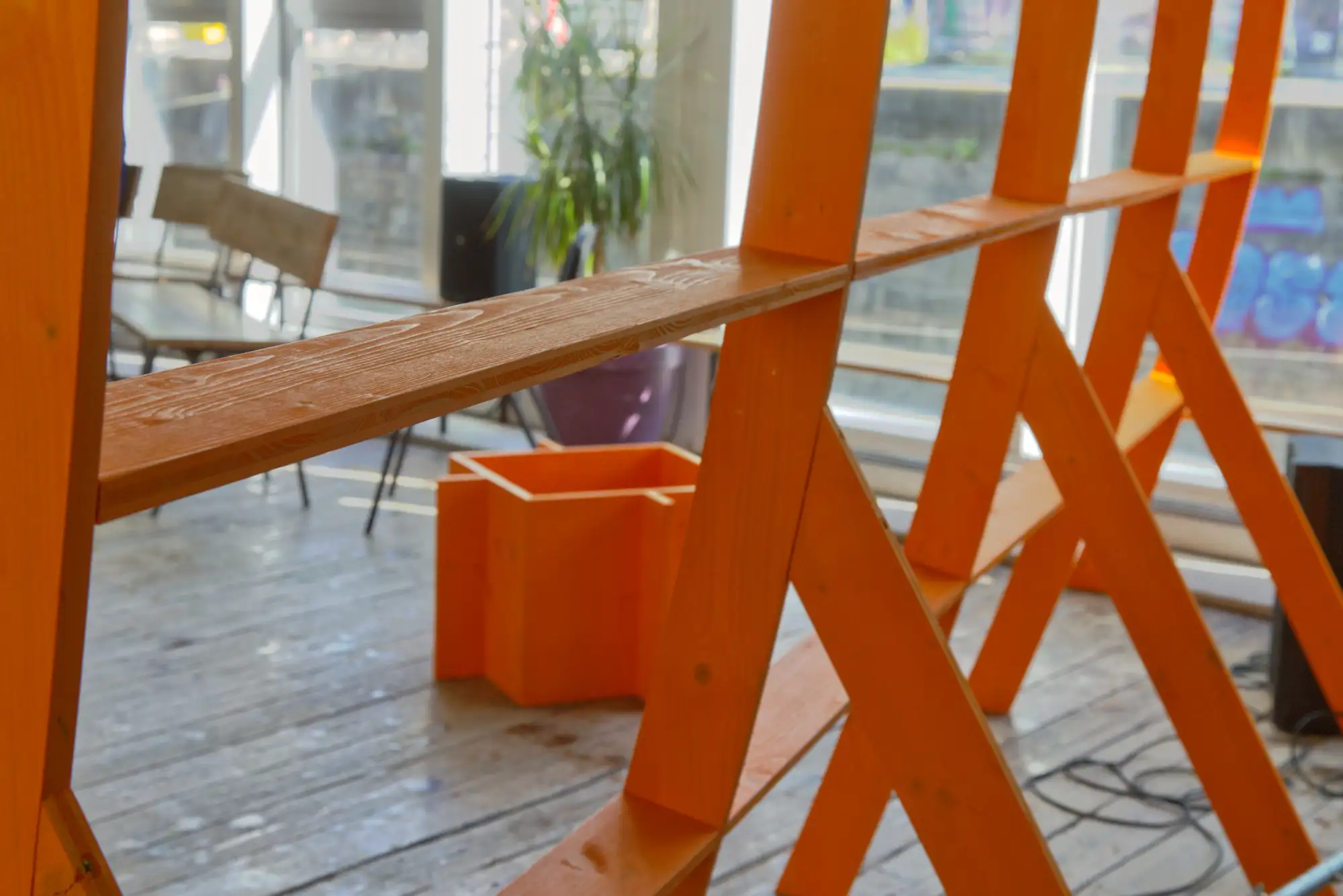 Ausschnitt eines orange gestrichenen Holzgerüstes.