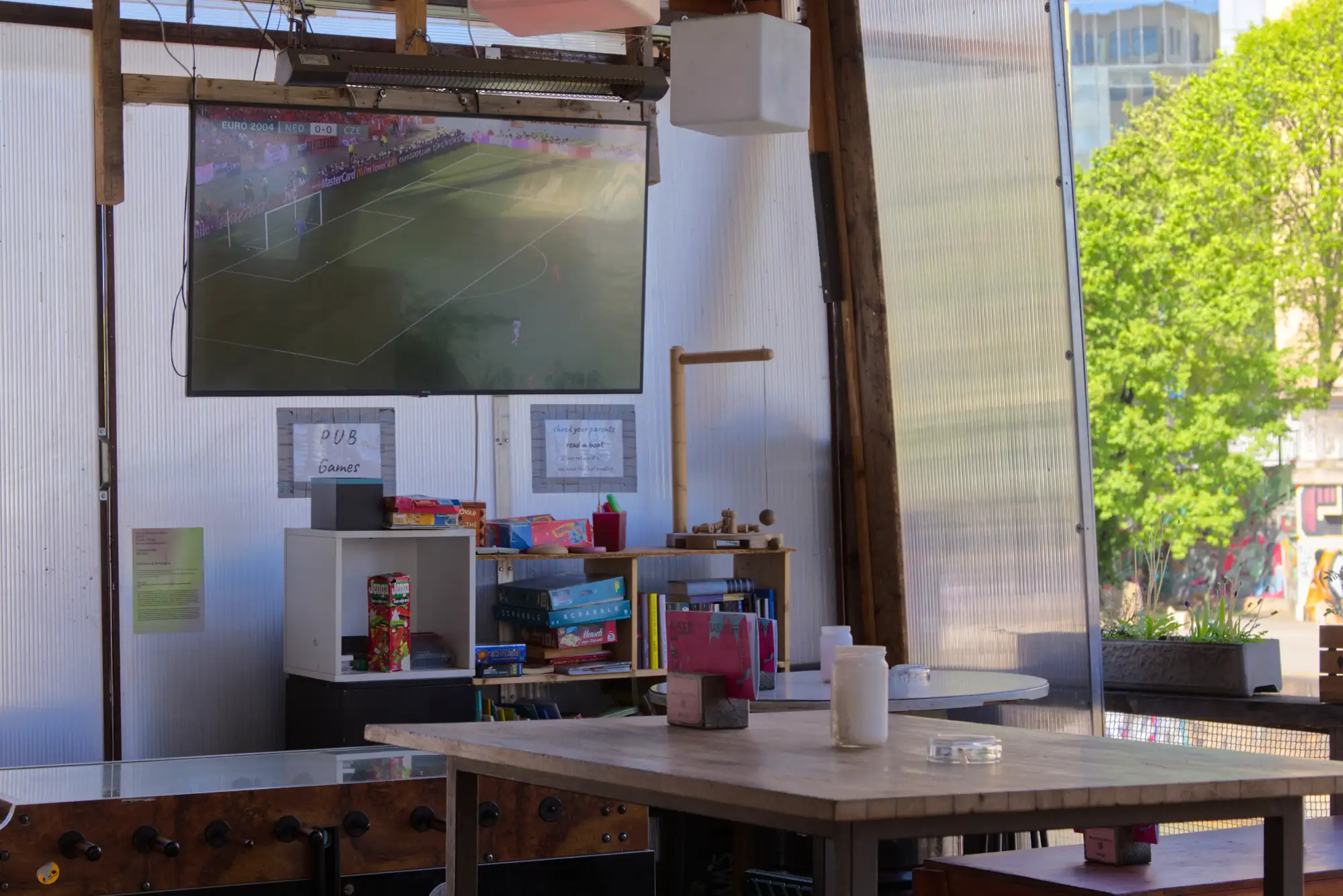 Ein Tisch in der Bar des Badeschiffs, an der Wand dahinter ein Screen, auf dem Fußball läuft.