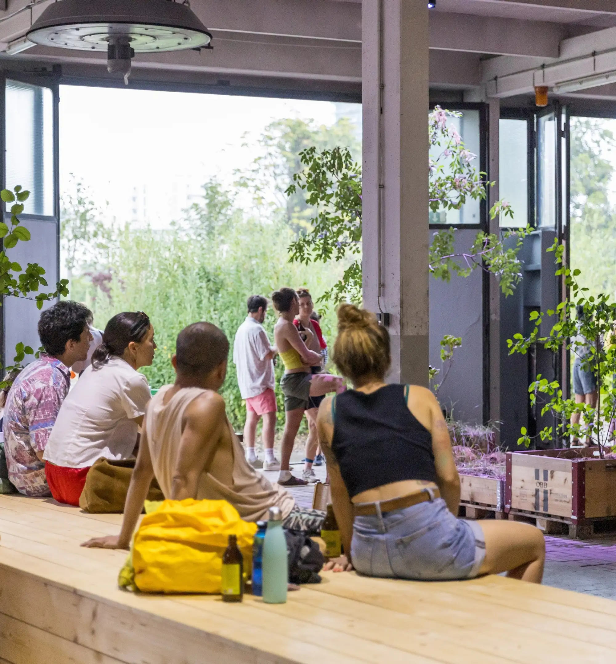 Menschen sitzen in einer offenen Halle mit Kunstwerken und betrachten Objekte