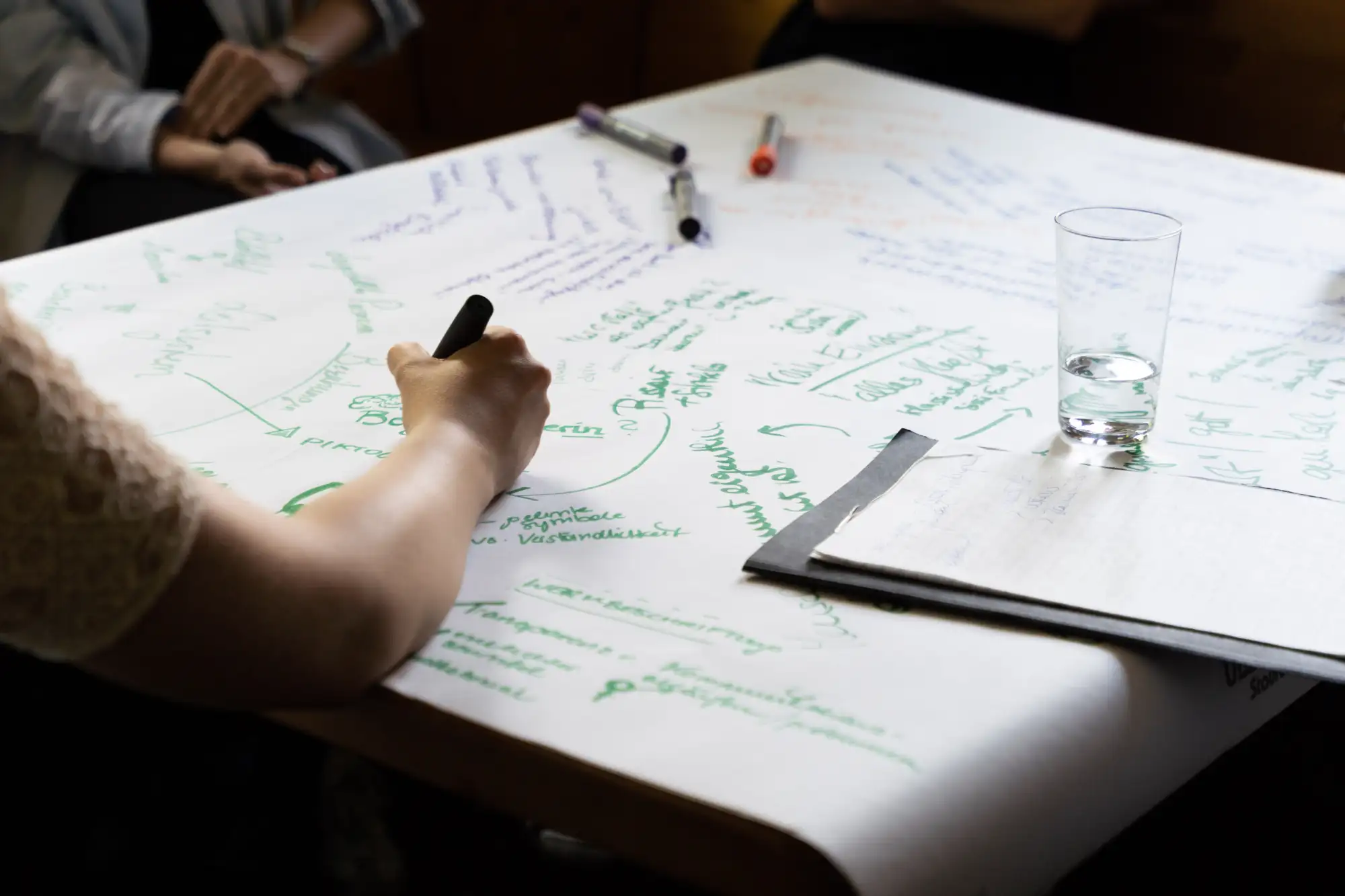 Person schreibt mit einem Stift auf einem weißen Flip Chart Blatt